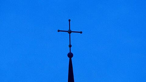 Ein Kreuz ist auf einer Kirchturmspitze zu sehen. Foto: Friso Gentsch/dpa/Symbolbild