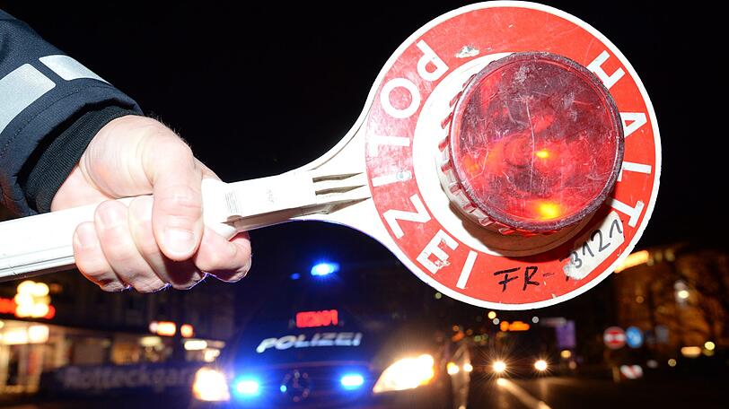 Eine Haltekelle der Polizei ist bei einer Alkoholkontrolle vor einem Polizeifahrzeug zu sehen.