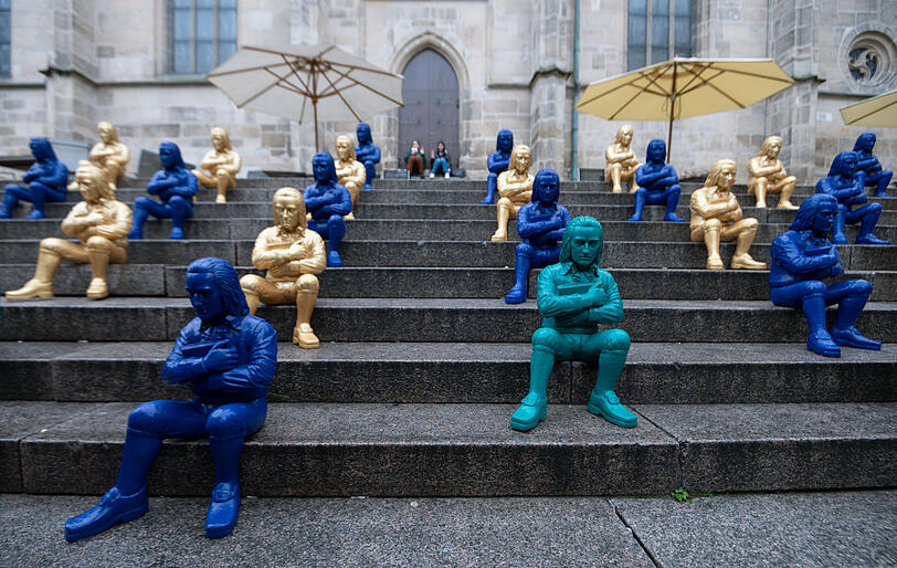 Figuren des Konzeptk&uuml;nstlers Ottmar H&ouml;rl, die den schw&auml;bischen Dichter Friedrich H&ouml;lderlin darstellen sollen, sitzen auf einer Treppe vor der Stiftskirche in T&uuml;bingen.