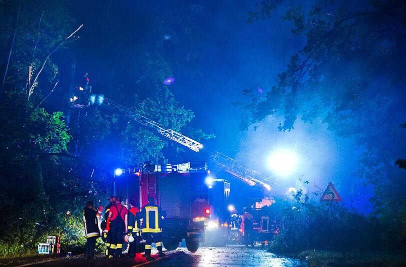 Feuerwehrleute versuchen am Sonntagabend in Bad Schwalbach (Hessen) umgestürzte Bäume von einer Straße zu räumen. Eine starke Windhose war zusammen mit einem Regensturm über den Kurort hinweggefegt und hatte Schäden in Millionenhöhe verursacht.
