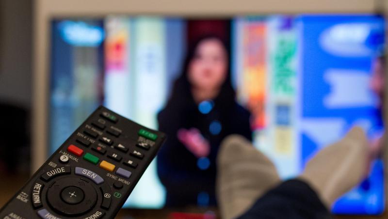 Eine Person sitzt vor einem Fernseher und hält eine Fernbedienung in der Hand. Foto: Monika Skolimowska/Archivbild