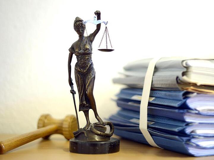 Justitia mit Holzhammer und Aktenstapel. Foto: Volker Hartmann/dpa/Symbolbild
