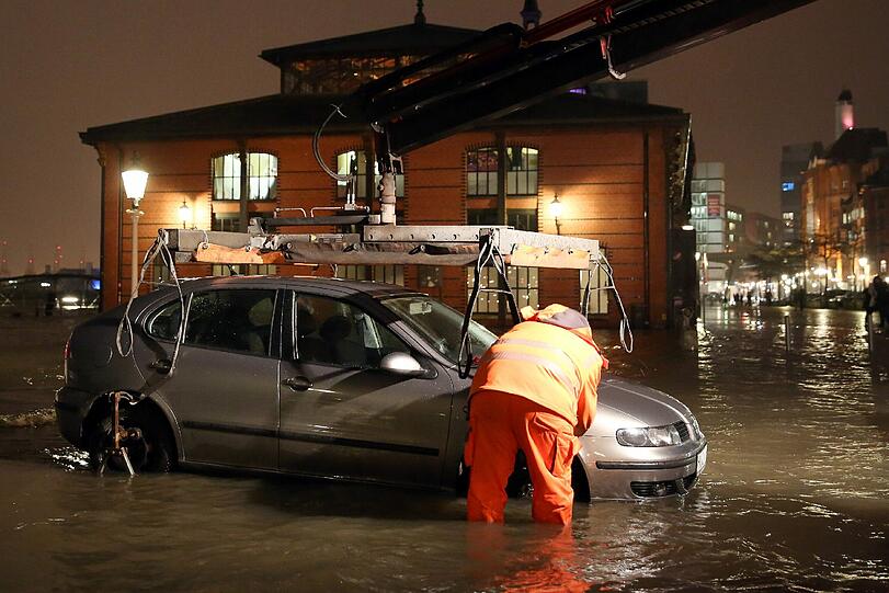 Ein Fahrzeug wird bei einer Sturmflut auf dem überfluteten Fischmarkt in Hamburg aus dem Wasser geschleppt.
