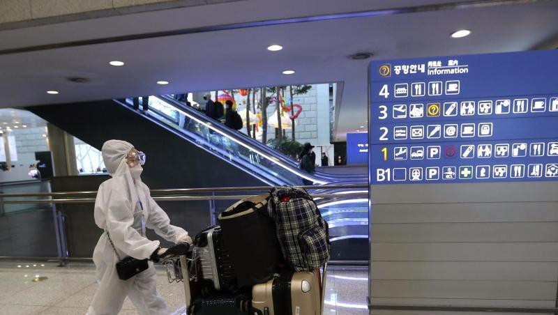 Eine Passagierin in Schutzkleidung schiebt am Flughafen Incheon einen Kofferwagen. Eine Passagierin in Schutzkleidung schiebt am Flughafen Incheon einen Kofferwagen.