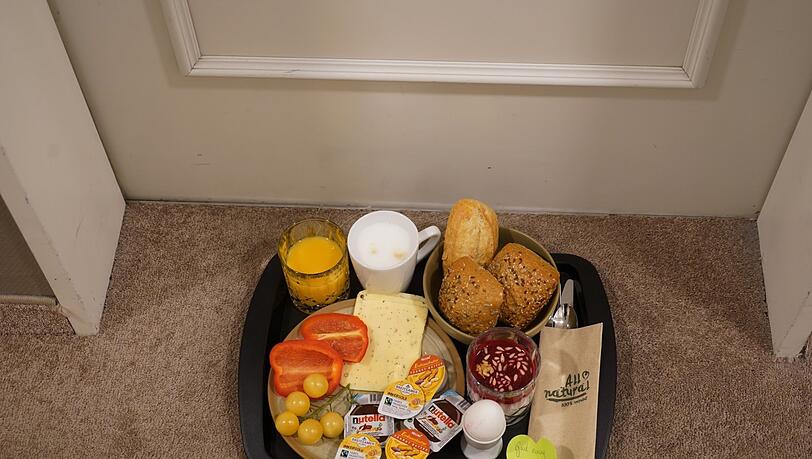Jeden Morgen liefern Hotelmitarbeiter ein Frühstückstablett vor dieZimmertür - mit Semmeln, Joghurt, Ei, Orangensaft und Käse. Jeden Morgen liefern Hotelmitarbeiter ein Frühstückstablett vor dieZimmertür - mit Semmeln, Joghurt, Ei, Orangensaft und Käse.
