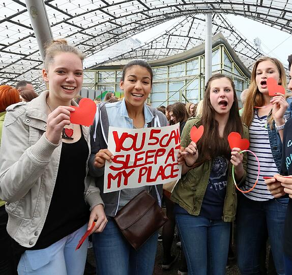 "One Direction" spielen am Freitag in der Olympiahalle. Jubelnde Fans warten im Regen vor der Olympiahalle.