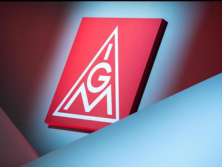 Das Logo der IG Metall hängt über einer Bühne. Foto: Daniel Karmann/dpa/Symbolbild