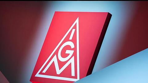 Das Logo der IG Metall hängt über einer Bühne. Foto: Daniel Karmann/dpa/Symbolbild