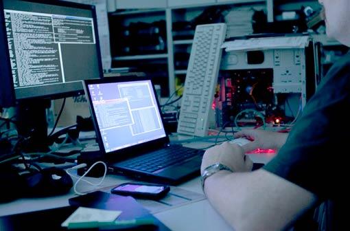 Ein Mann sitzt vor verschiedenen Computern und Monitoren.