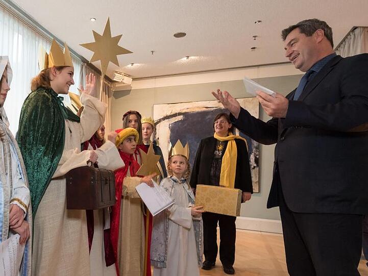 Der bayerische Ministerpräsident Markus Söder (CSU) überreicht Briefumschläge mit Spenden an die Sternsinger. Foto: Peter Kneffel