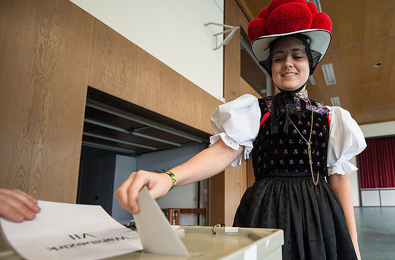 Eine Frau in der traditionellen Schwarzwälder Bollenhuttracht wirft in Kirnbach (Baden-Württemberg) ihren Stimmzettel in die Wahlurne.