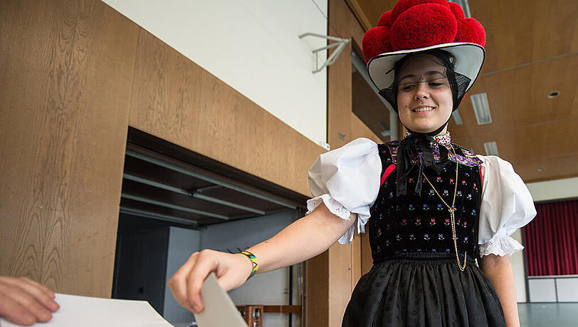 Eine Frau in der traditionellen Schwarzwälder Bollenhuttracht wirft in Kirnbach (Baden-Württemberg) ihren Stimmzettel in die Wahlurne. Eine Frau in der traditionellen Schwarzwälder Bollenhuttracht wirft in Kirnbach (Baden-Württemberg) ihren Stimmzettel in die Wahlurne.