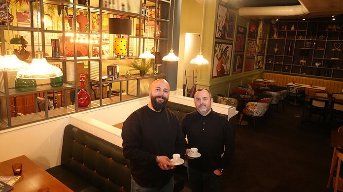 El presentador Ferhat Pierre (izquierda) y Sebastian Meyer toman café la noche anterior a la inauguración después de varios turnos nocturnos.  Realmente trabajamos hasta el último minuto.