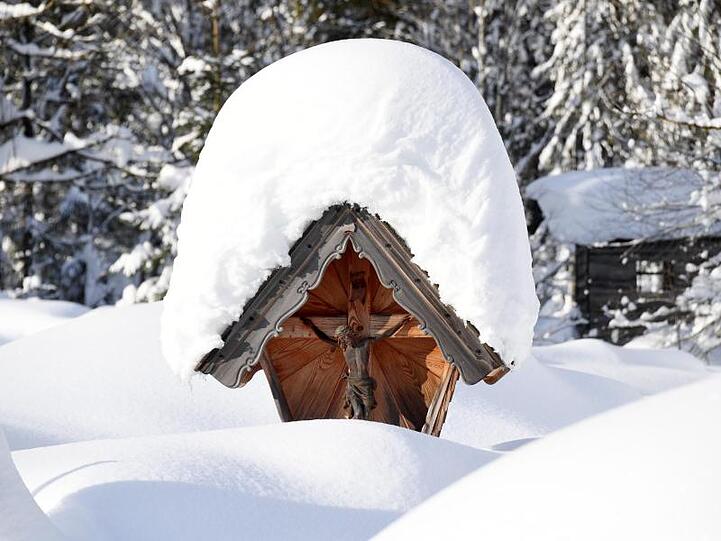 Schnee bedeckt eine Christusfigur. Foto: Tobias Hase/Archiv