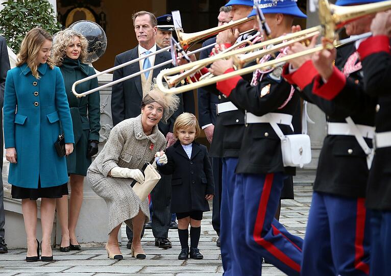 Hier spielt am Nationalfeiertag von Monaco die Musik: Prinzessin Caroline (wie immer top angezogen) geht in die Knie, um näher bei ihrem Enkelsohn Sacha Casiraghi zu sein. Tochter Alexandra von Hannover (l.) schaut ihrer Mama amüsiert zu.