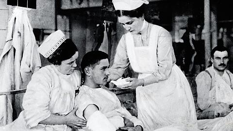 Eine typische Szene: Dieses undatierte Foto aus dem Ersten Weltkrieg zeigt zwei Rotkreuzschwestern, die einem verwundeten Soldaten etwas zu trinken reichen.