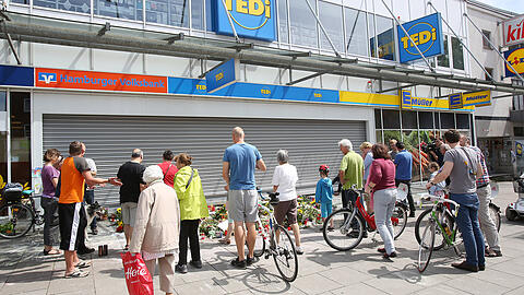 Passanten stehen vor dem Supermarkt in Hamburg-Barmbek, in dem ein Mann einen Menschen mit einem Messer getötet und sechs weitere verletzt hat.