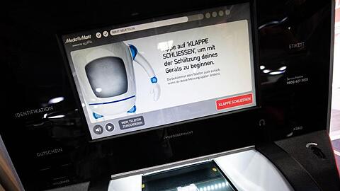 Ein Handy liegt in dem optischen Mechanismus eines "EcoATM" in einer MediaMarkt Filiale. Foto: Lino Mirgeler