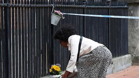 Eine Frau legt zum Gedenken an die Opfer im Stadtzentrum von Reading Blumen nieder.