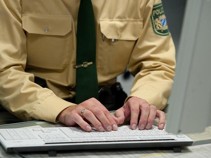 Ein Polizist schreibt auf einer Polizeidienststelle auf einer Computertastatur. Foto: Armin Weigel/Archiv