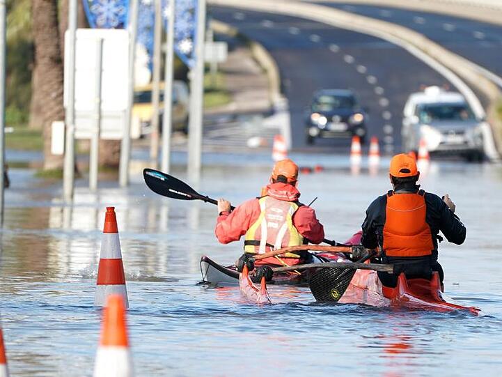 Zwei Männer paddeln mit ihren Kajaks durch die überflutete Straße in Palavas-les-Flots nach einem nächtlichen Sturm in Südfrankreich.