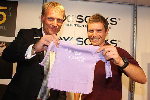 Wöhrl Sportchef Oliver Schiemann übergibt bei der 75-Jahr-Feier Babysachen an Skilanglauf-Star Tobias Angerer.