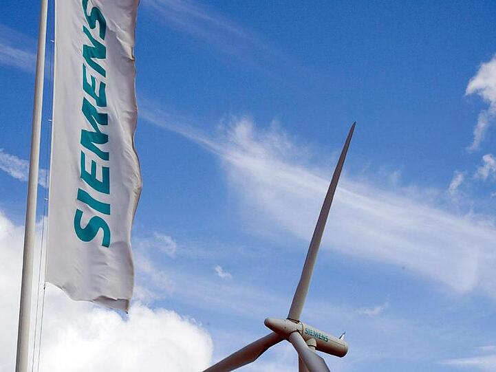 Eine Siemens-Fahne und eine Windkraftanlage sind zu sehen. Foto: Jürgen Winzeck/Siemens/dpa/Archivbild