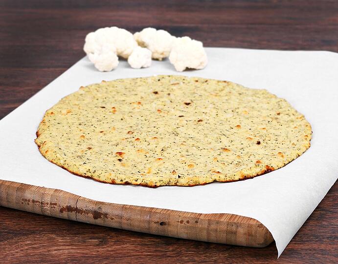 Im n&auml;chsten Schritt das Blumenkohl-Mehl zusammen mit geriebenem K&auml;se, Ei, Knoblauch, Kr&auml;uter und Salz zu einem Teig kneten. Danach die Masse d&uuml;nn auf einem Backblech ausrollen und f&uuml;r zehn Minuten ohne Topping im Ofen backen. Erst danach wird die Pizza mit Tomatensauce und Belag nach Wahl bestreut und weitere zehn Minuten in den Ofen geschoben.