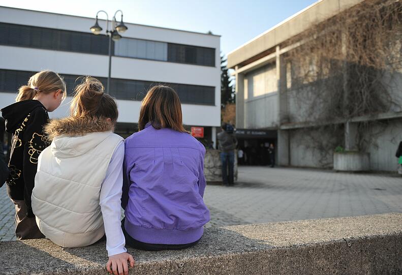 Mödchen sitzen vor der Kirche in der Abendsonne.