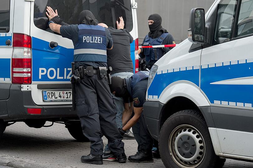Polizisten durchsuchen auf dem Gelände des Flughafens Frankfurt einen Mann.
