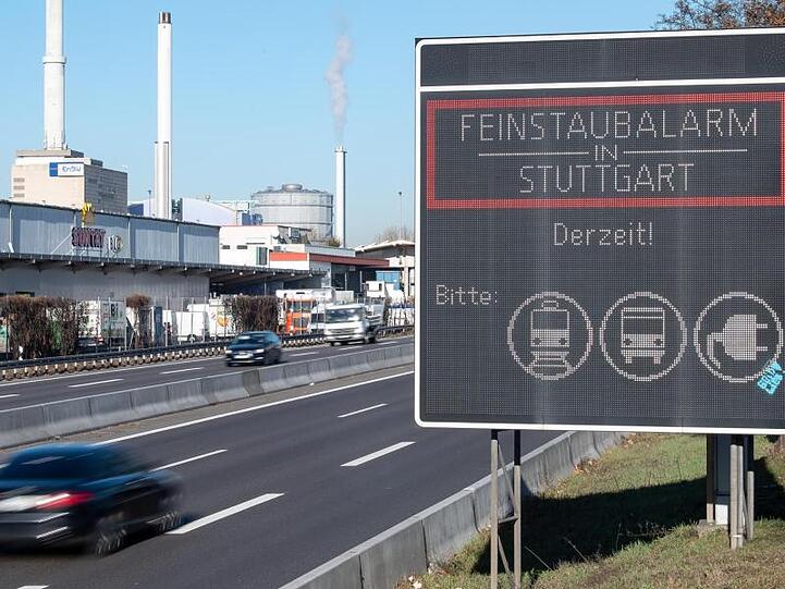 Ein Auto fährt an einem Schild vorbei, das auf den geltenden Feinstaubalarm in Stuttgart hinweist.