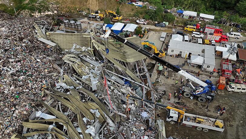 Die Einsatzkr&auml;fte suchen unter anderem mit einem Kran in den Abfall-Massen.