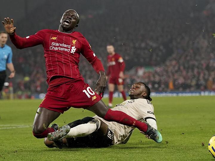 Liverpools Sadio Mane (l) wird von Manchesters Aaron Wan-Bissaka im Zweikampf von den Beinen geholt.