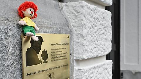 Eine Pumuckl-Figur sitzt auf einer Gedenktafel zu Ehren des Schauspielers Gustl Bayrhammer.