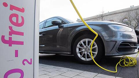 Ein Elektroauto von Audi wird mit einem Kabel an einer E-Ladesäule aufgeladen.