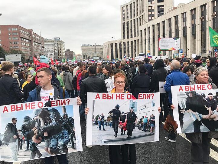 Zahlreiche Menschen demonstrieren mit Flaggen, Fahnen und Plakaten gegen Polizeigewalt und für freie Wahlen.