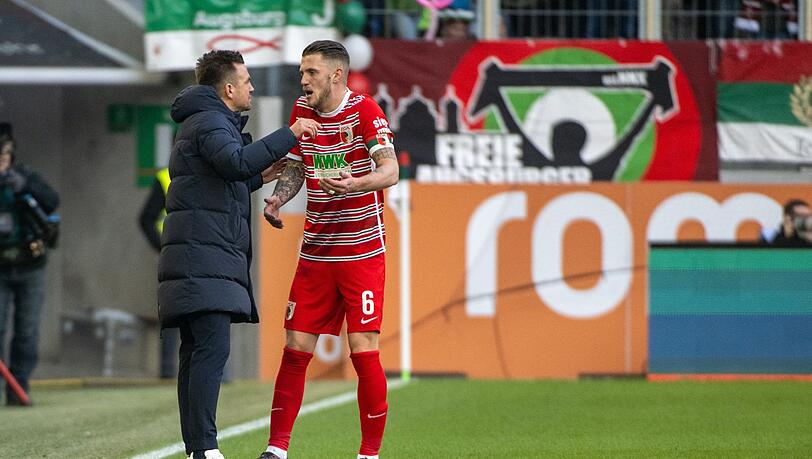 Augsburgs Trainer Enrico Maaßen (l) spricht mit Jeffrey Gouweleeuw.