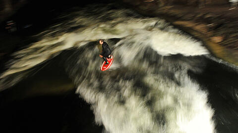 Ein Mann surft 2019 bei Flutlicht auf der künstlichen Welle des Eisbaches im Englischen Garten. (Symbolbild)