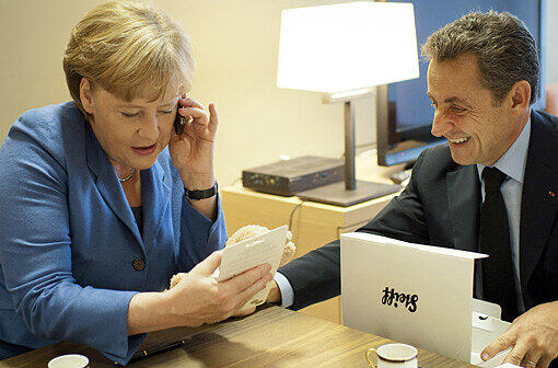 Baby-Geschenk: Angela Merkel überreicht Sarkozy hinter den Kulissen einen Teddybären für die kleine Giulia.