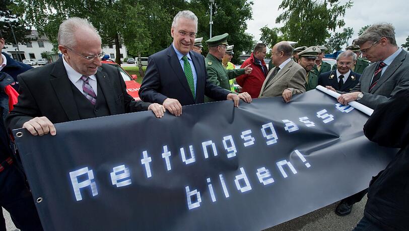 Innenminister Joachim Herrmann (M.) wirbt mit einem Plakat mit der Aufschrift „Rettungsgasse bilden!“ Innenminister Joachim Herrmann (M.) wirbt mit einem Plakat mit der Aufschrift „Rettungsgasse bilden!“