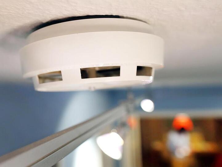 Ein Rauchmelder ist an der Decke in einem Hausflur angebracht.