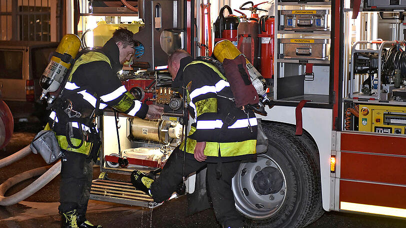 Zwei Feuerwehrmänner reinigen ihre Stiefel nach dem Einsatz in der stark verrauchten Wohnung.