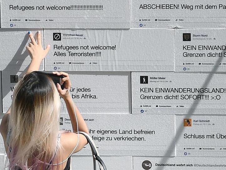 Eine Frau schaut sich auf dem Berliner Gendarmenmarkt eine Mauer an, auf die sogenannte "hate speech" gedruckt ist. Die Mauer voller Hass-Botschaften wurde symbolisch zum Einsturz gebracht.
