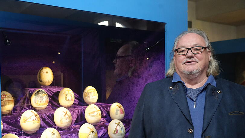 J&uuml;rgen Milla vor einem Satz k&uuml;nstlicher Strau&szlig;eneier, die er mit dem Kreuzweg bemalt hat.