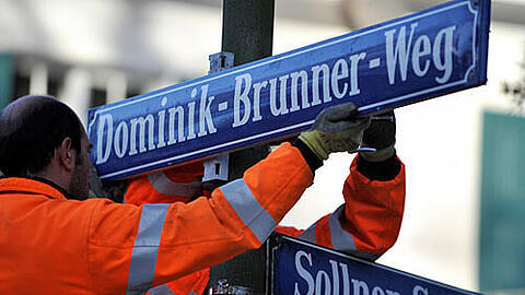 Mitarbeiter des Baureferats bringen die Straßenschilder "Dominik-Brunner-Weg" an
