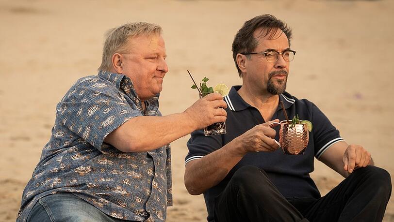 "Tatort: Unter G&auml;rtnern": Boerne (Jan Josef Liefers, r.) und Thiel (Axel Prahl) genie&szlig;en einen Drink - Cuba Libre und Moscow Mule - am Strand.