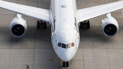 Ein Vorfeld-Arbeiter geht auf einem Flughafen an einem startbereiten Jet der Lufthansa vorbei.
