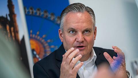 Münches neuer Wiesnchef Scharpf vor einem Foto des Riesenrades.