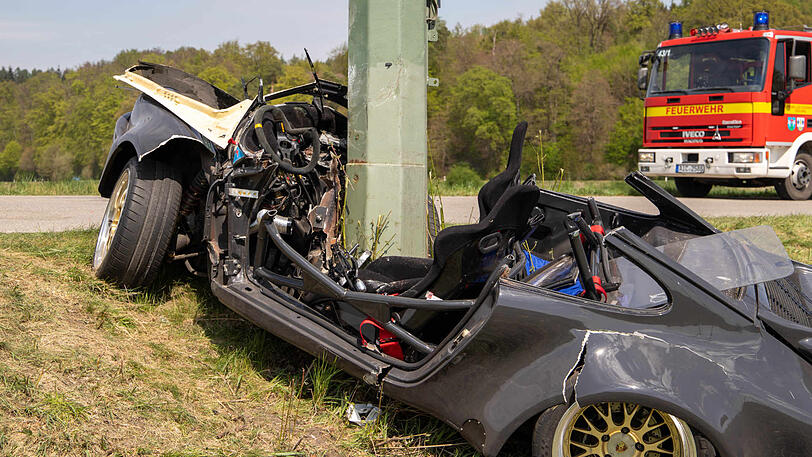 Ein Strommast ragt aus einem Porsche, nachdem dieser in einer leichten Rechtskurve von der Straße abgekommen und gegen den Masten geprallt ist.