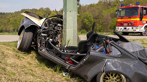 Ein Strommast ragt aus einem Porsche, nachdem dieser in einer leichten Rechtskurve von der Straße abgekommen und gegen den Masten geprallt ist.
